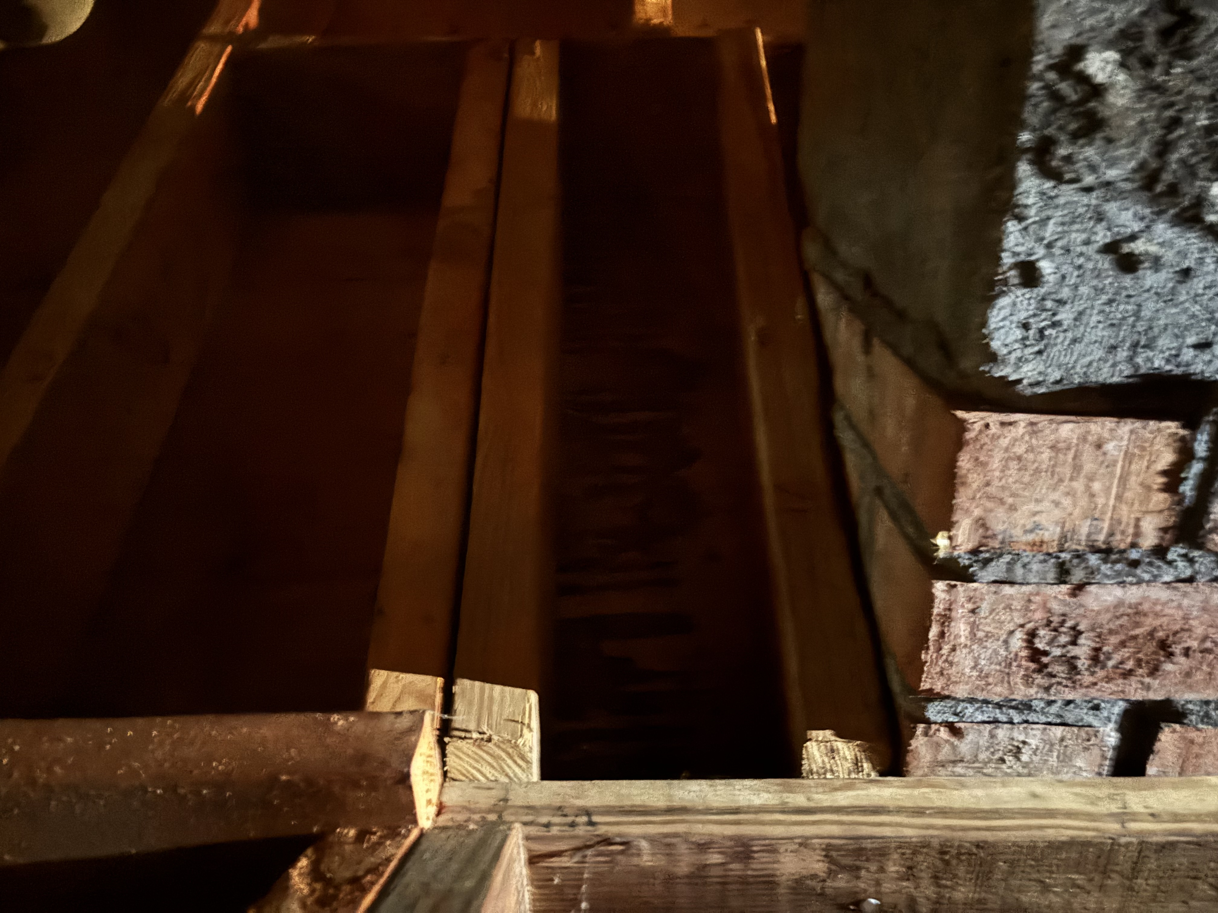 Cracked roof rafter and inadequate framing at chimney connection—an example of a hidden structural issue where small defects can create significant load risk and require immediate repair.