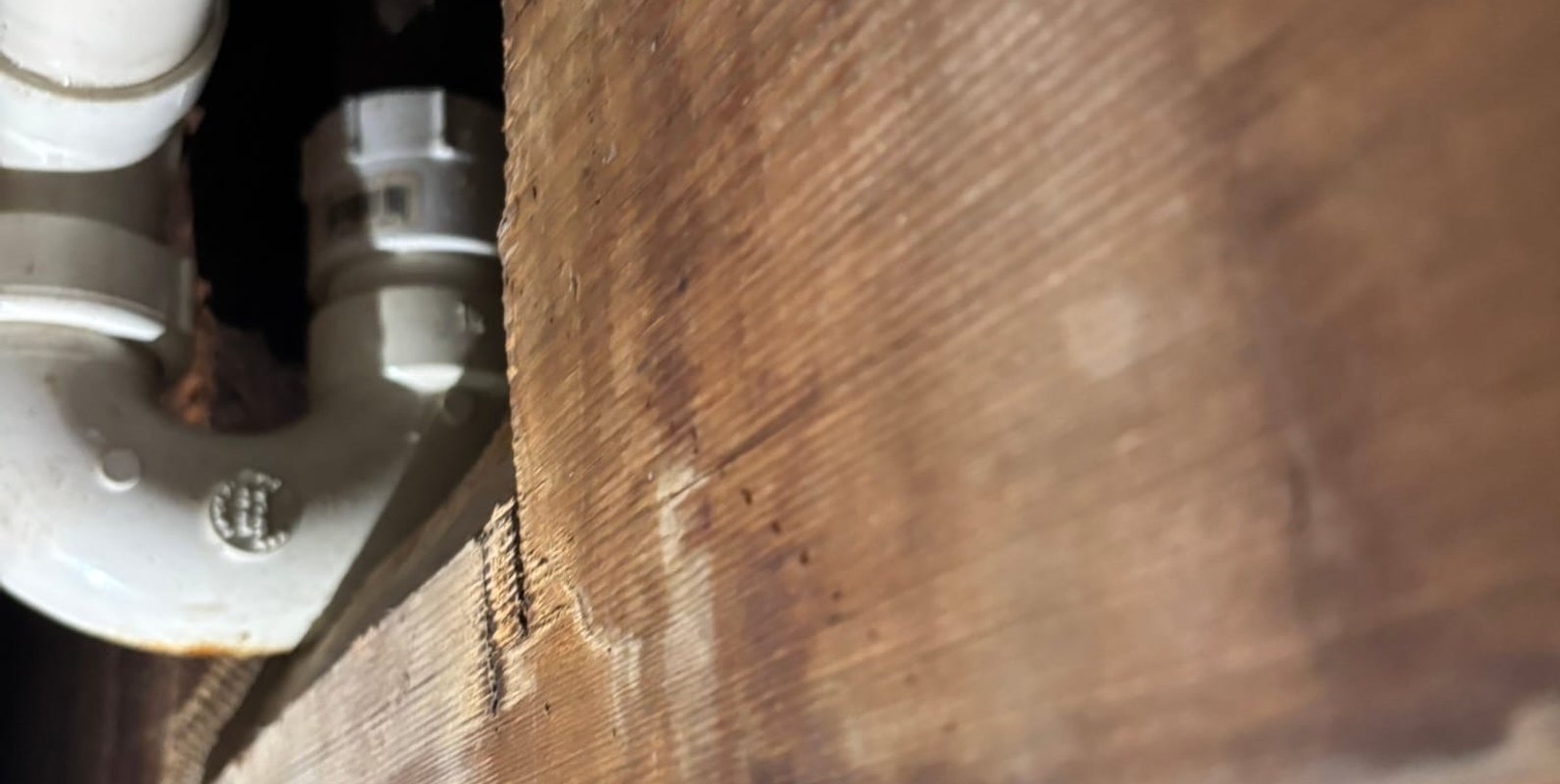 Basement plumbing penetration where floor joists were cut and modified during a remodeling project—an example of improper alterations to structural framing that contributed to code deficiencies and disrupted a real estate transaction.