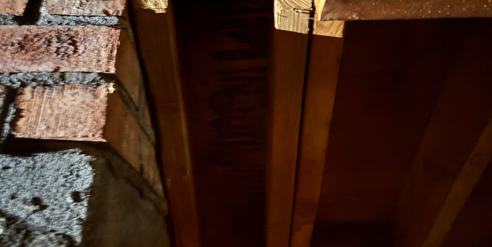 Cracked roof rafter and inadequate framing at chimney connection—an example of a hidden structural issue where small defects can create significant load risk and require immediate repair.